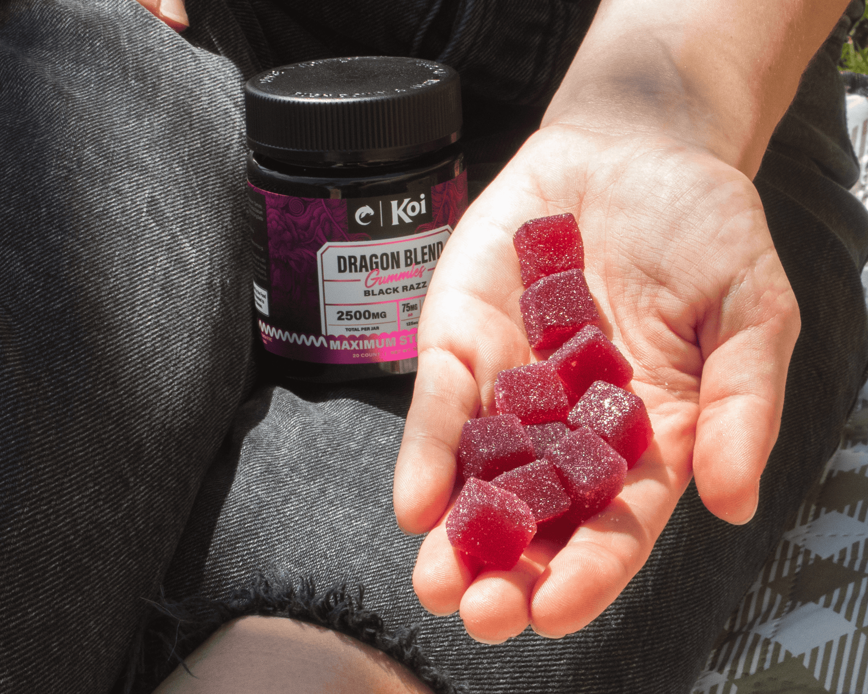 Person holding red gummies with a Koi CBD product in the background